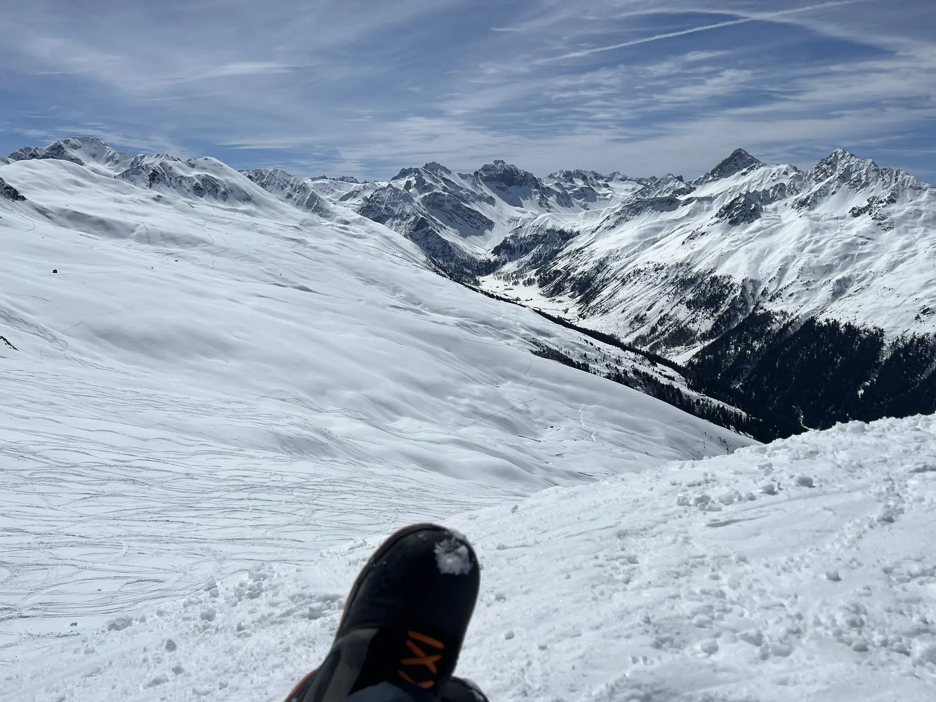 Freeride-Perspektive am Jakobshorn: Snowboardboot vor weitem Bergpanorama