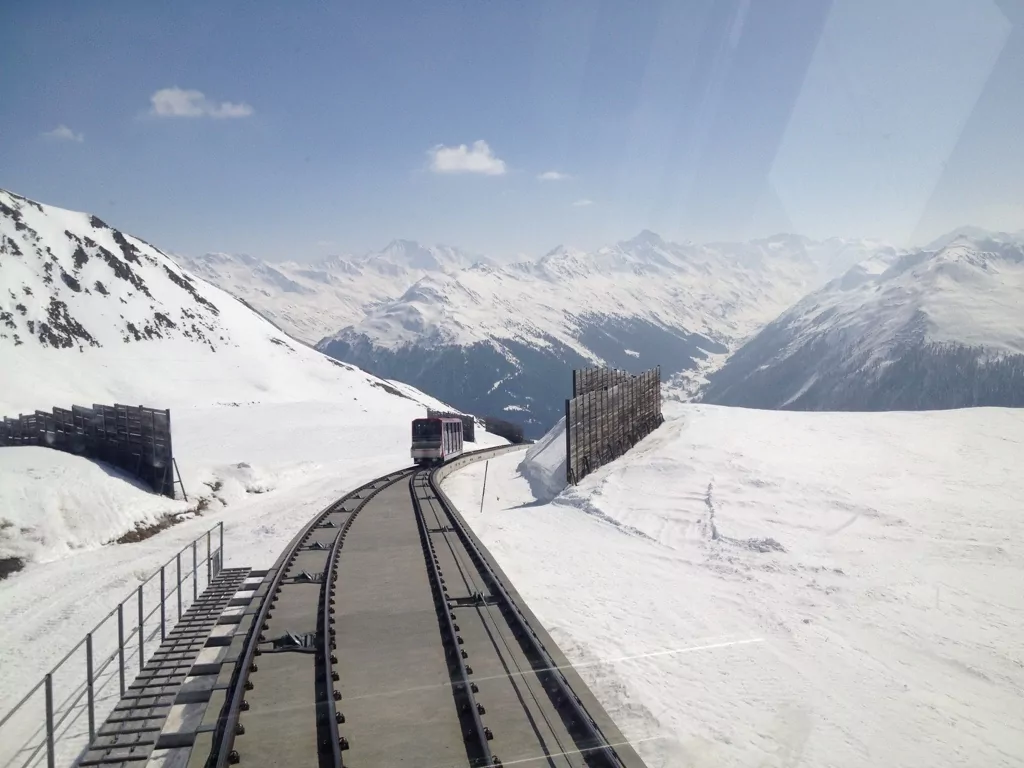Rote Standseilbahn der Parsennbahn auf der verschneiten Bergstrecke, entgegenkommender Wagen an der Ausweiche