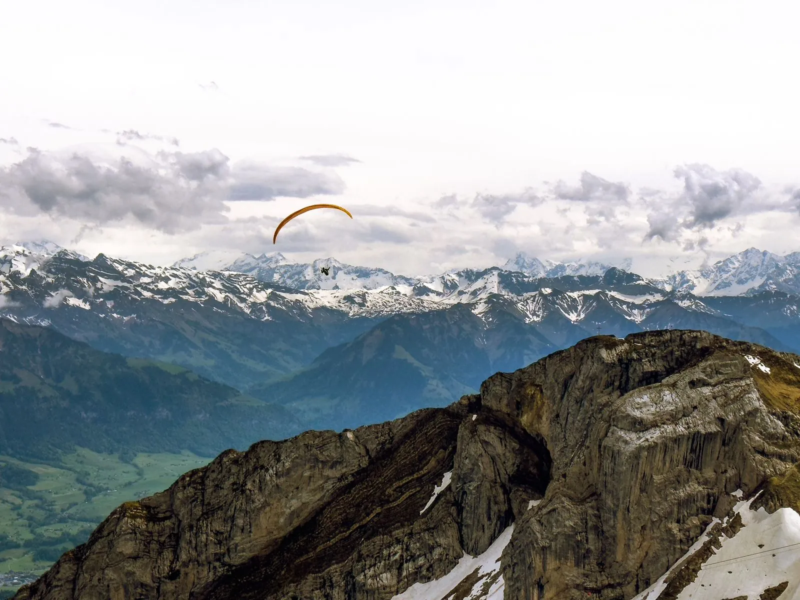 Gleitschirm über Alpengipfeln (Symbolbild)